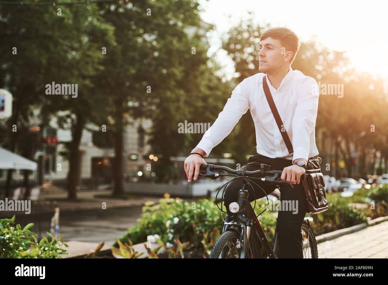 Verano verde de los árboles en el fondo. Empresario de ropa formal con el  negro de la bicicleta en la ciudad Fotografía de stock - Alamy