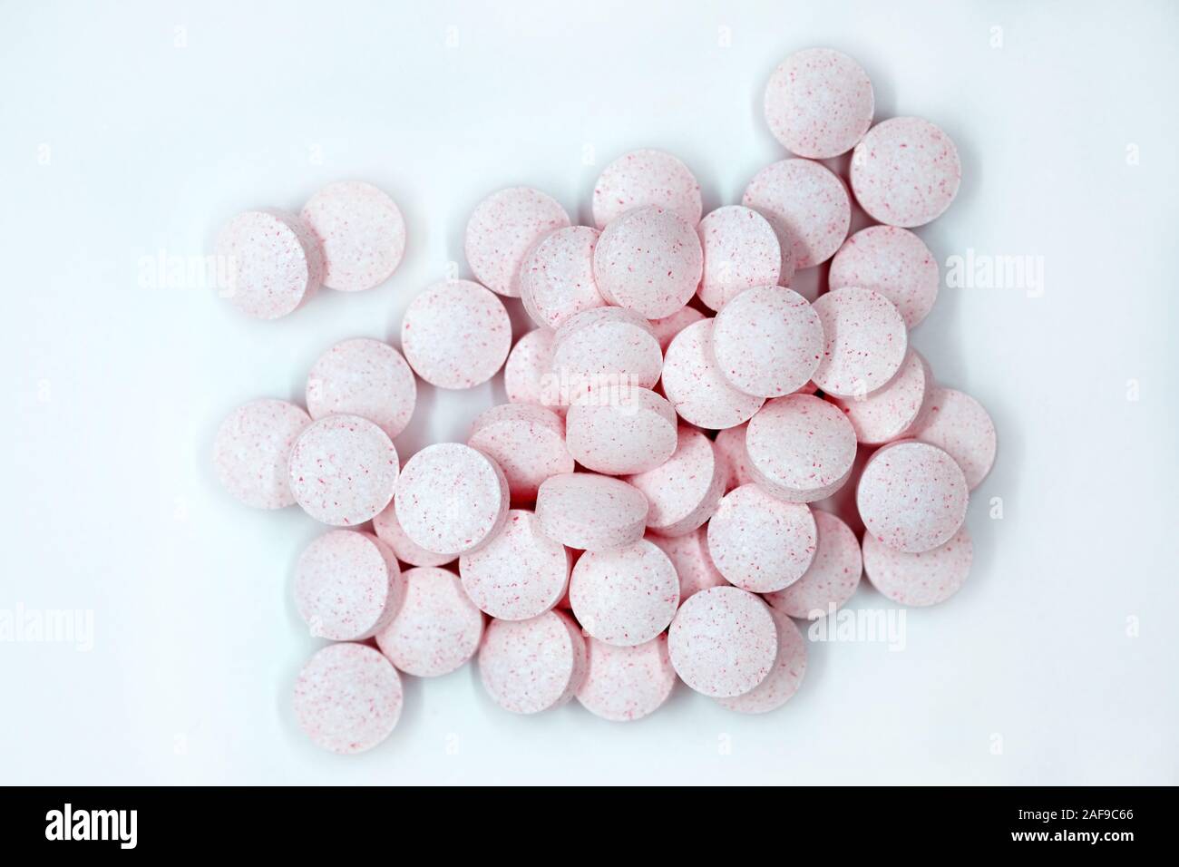 Píldoras de Rosa sobre un fondo gris vista desde arriba. Las vitaminas