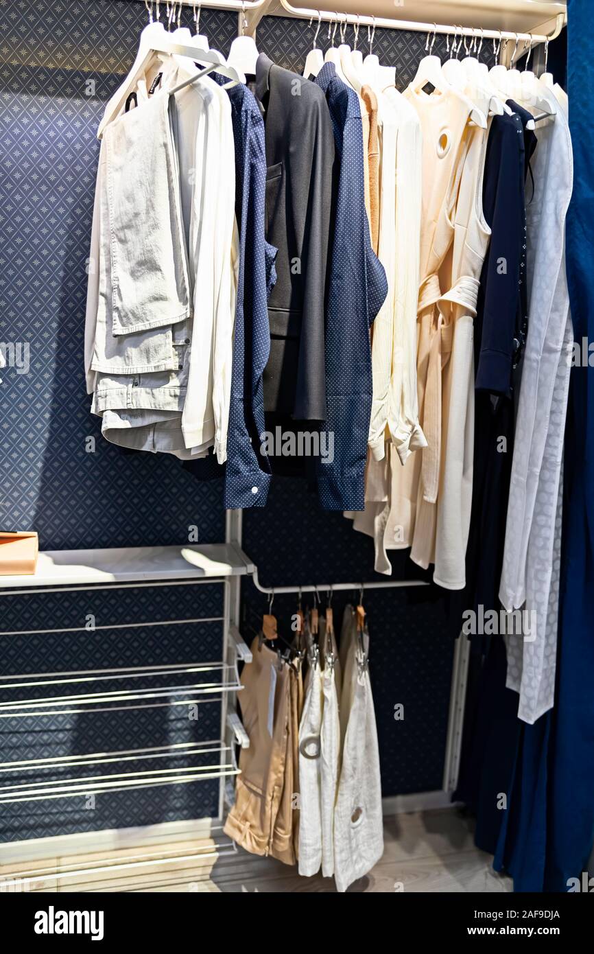 Un número de diferentes colgar la ropa en perchas en un moderno armario azul.  Cómodo almacenamiento Fotografía de stock - Alamy