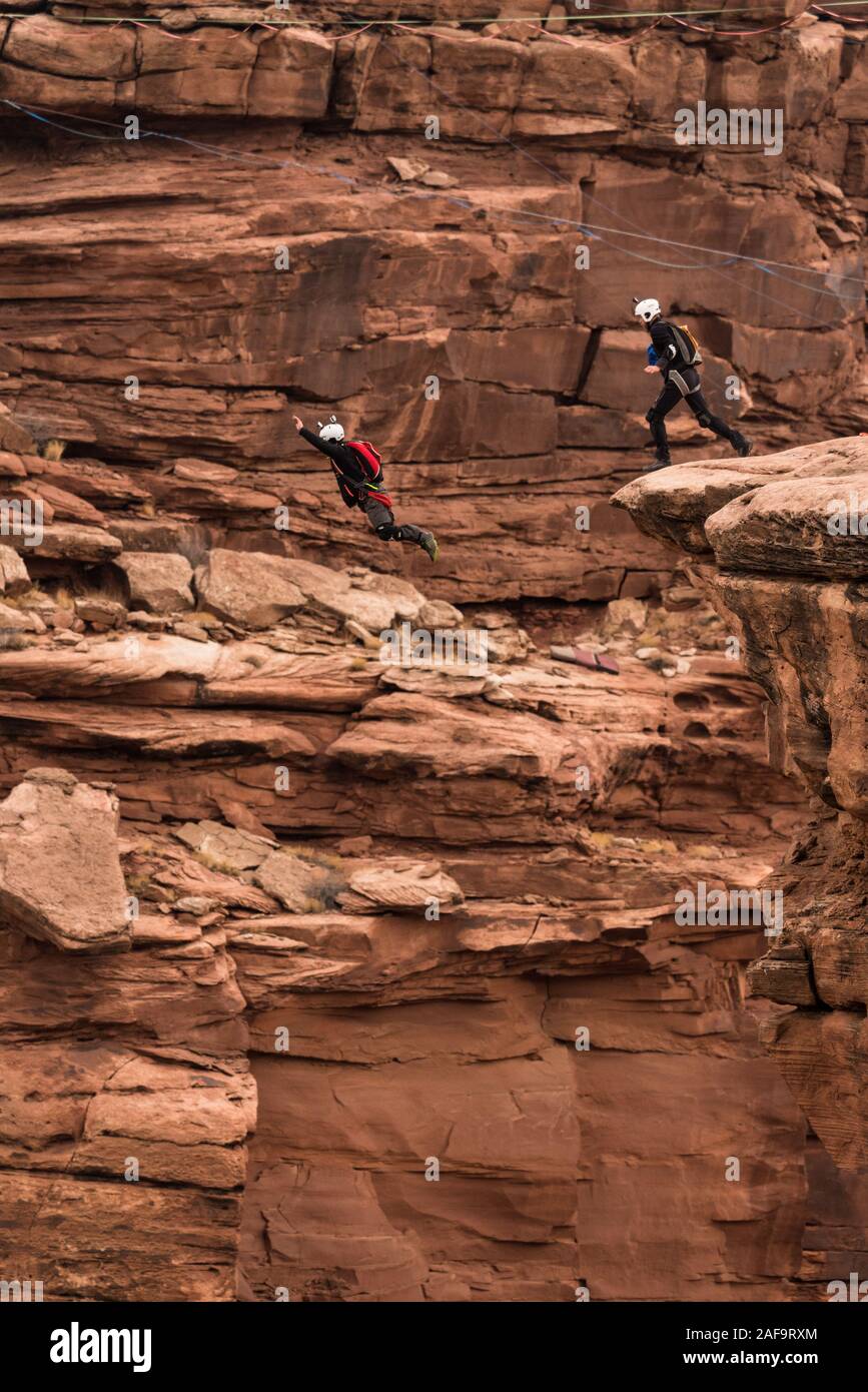Dos saltadores base saltar del acantilado de 950 pies sobre el piso de Mineral Canyon, cerca de Moab, Utah. Foto de stock