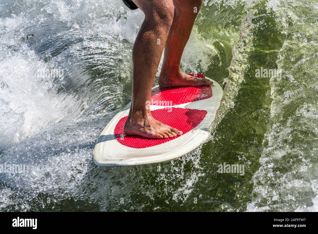 Un hombre joven wake surf detrás de un bote en el Lago Powell en el Glen Canyon National Recreation Area, en el sur de Utah, EE.UU.. Foto de stock