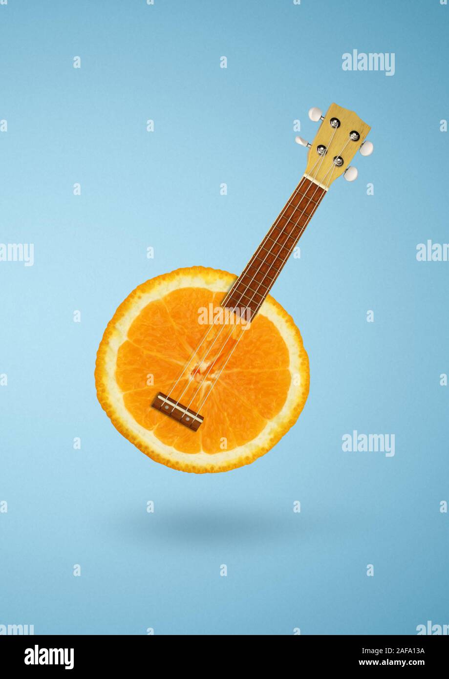 El concepto creativo, como guitarra naranja sobre fondo azul. Foto de stock