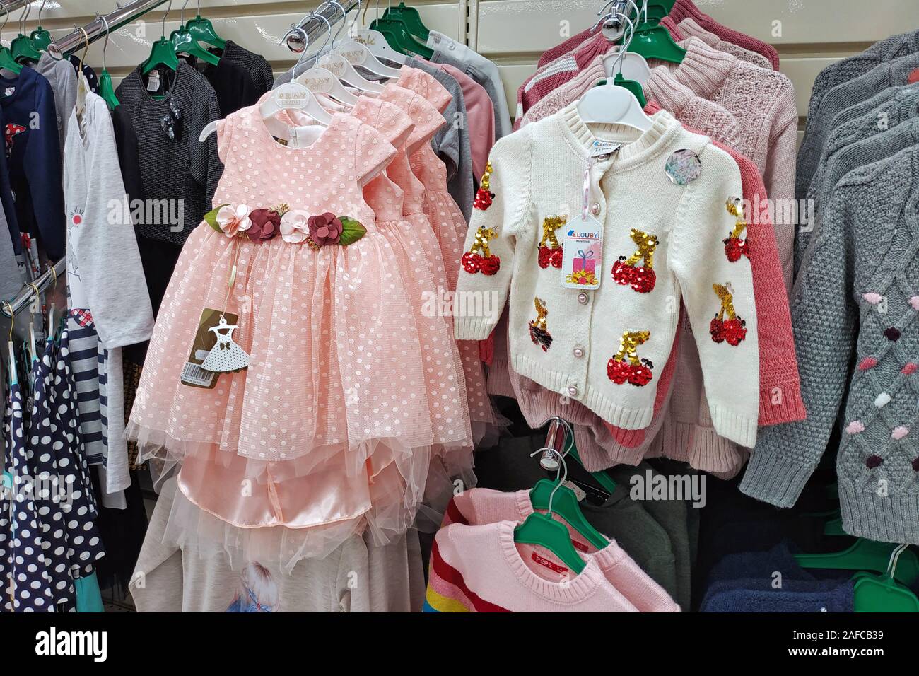 Prendas de vestir para niños en la tienda. Una nueva colección de ropa de  moda se cuelga en una boutique. Suéteres, brillante vestido rosado tema de  Navidad Fotografía de stock - Alamy