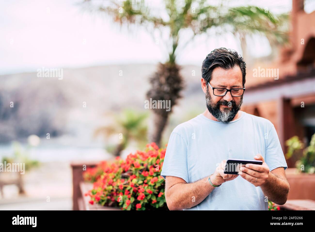 Tipo de hombre en un moderno dispositivo de teléfono celular en actividad de ocio al aire libre con la tecnología - retrato de edad adulta con efecto de desenfoque de fondo Foto de stock