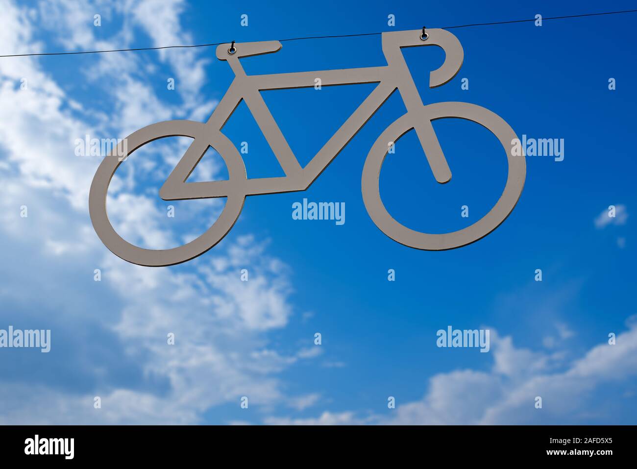 Carril Bici, símbolo gris de una bicicleta colgando de un cable en un cielo  azul con nubes. Italia Fotografía de stock - Alamy