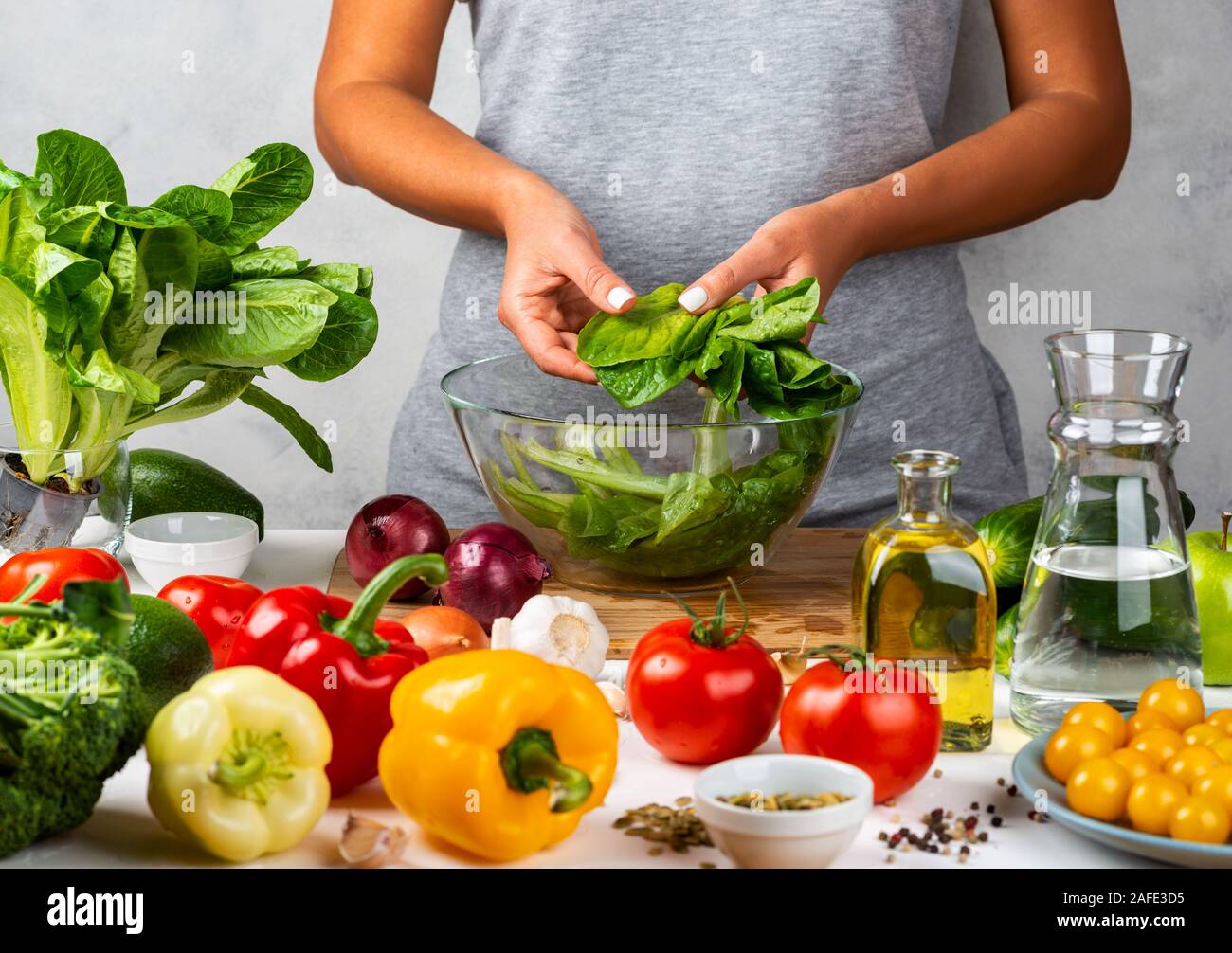 La mujer está preparando ensalada verde de lechuga romana, cocinar ensalada en un recipiente de cristal en la cocina. Concepto de dieta saludable. Foto de stock