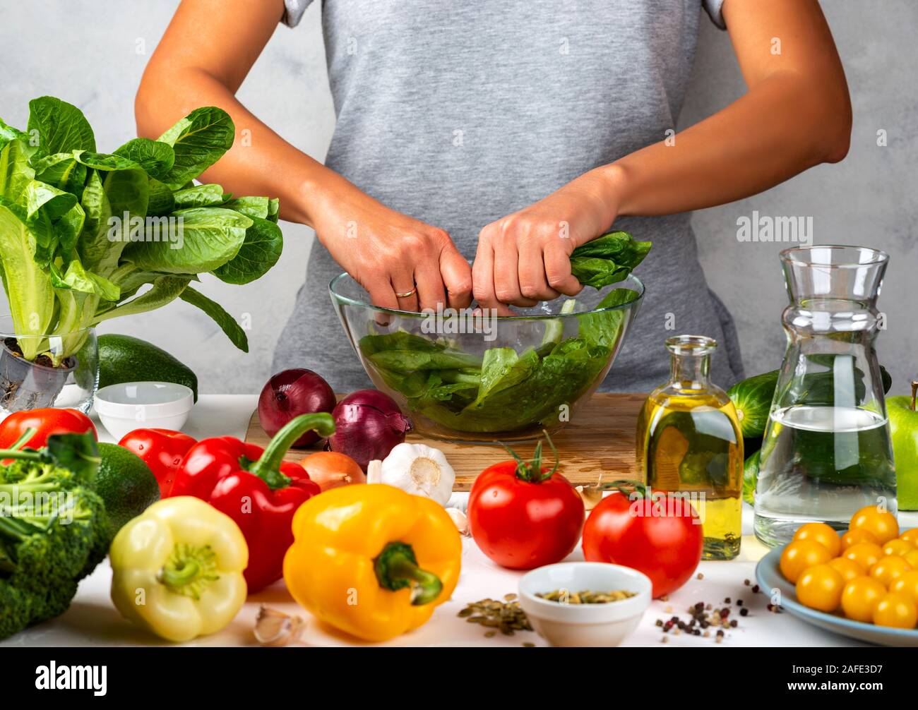 La mujer está preparando ensalada verde de lechuga romana, cocinar ensalada en un recipiente de cristal en la cocina. Concepto de dieta saludable. Foto de stock