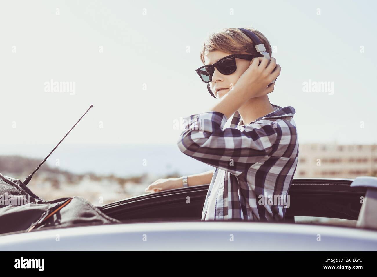 Retrato de moda joven escuchando música y mirando el panorama que sale del  techo abierto de un coche. Teen disfrutando de un hermoso día de primavera  Fotografía de stock - Alamy