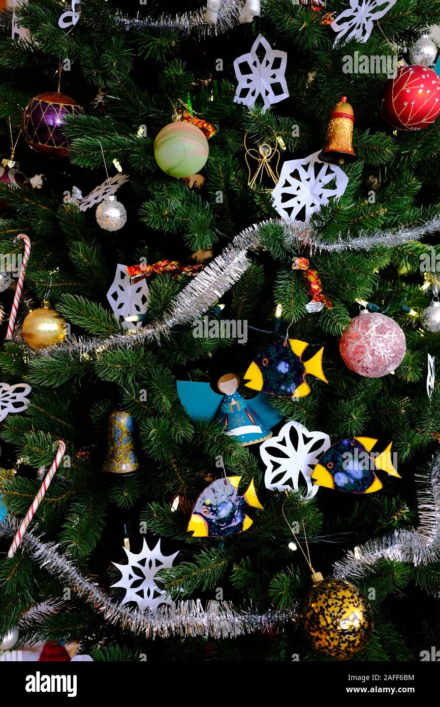Cerca del árbol de Navidad con adornos, luces, bolas, guirnaldas, papel copos de nieve, bastones de caramelo, cerámica de pescado, etc. Foto de stock