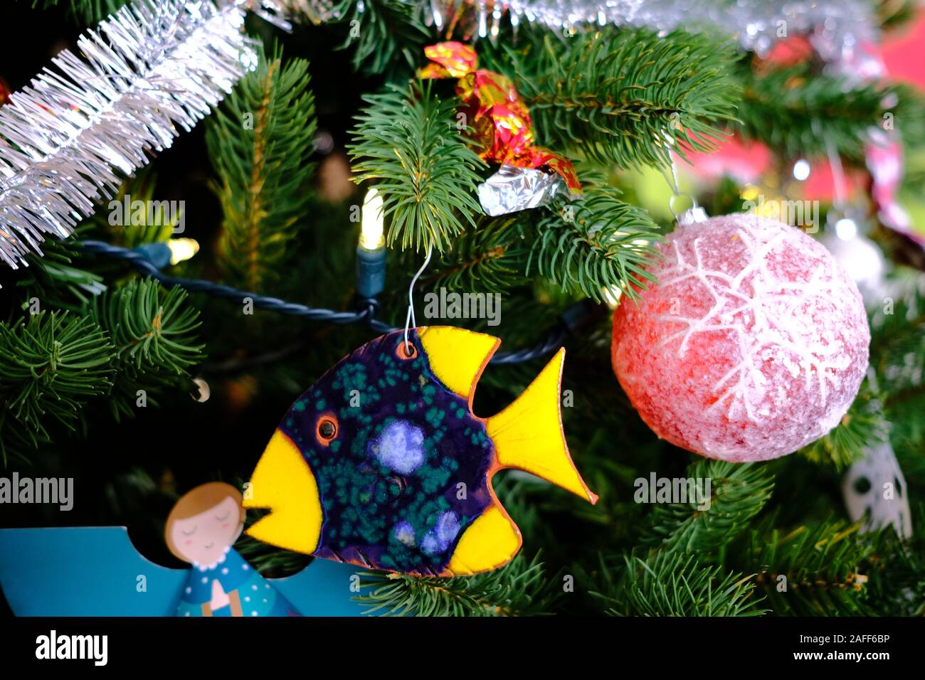 Cerca del árbol de Navidad con adornos, luces, bolas, guirnaldas, papel copos de nieve, bastones de caramelo, cerámica de pescado, etc. Foto de stock