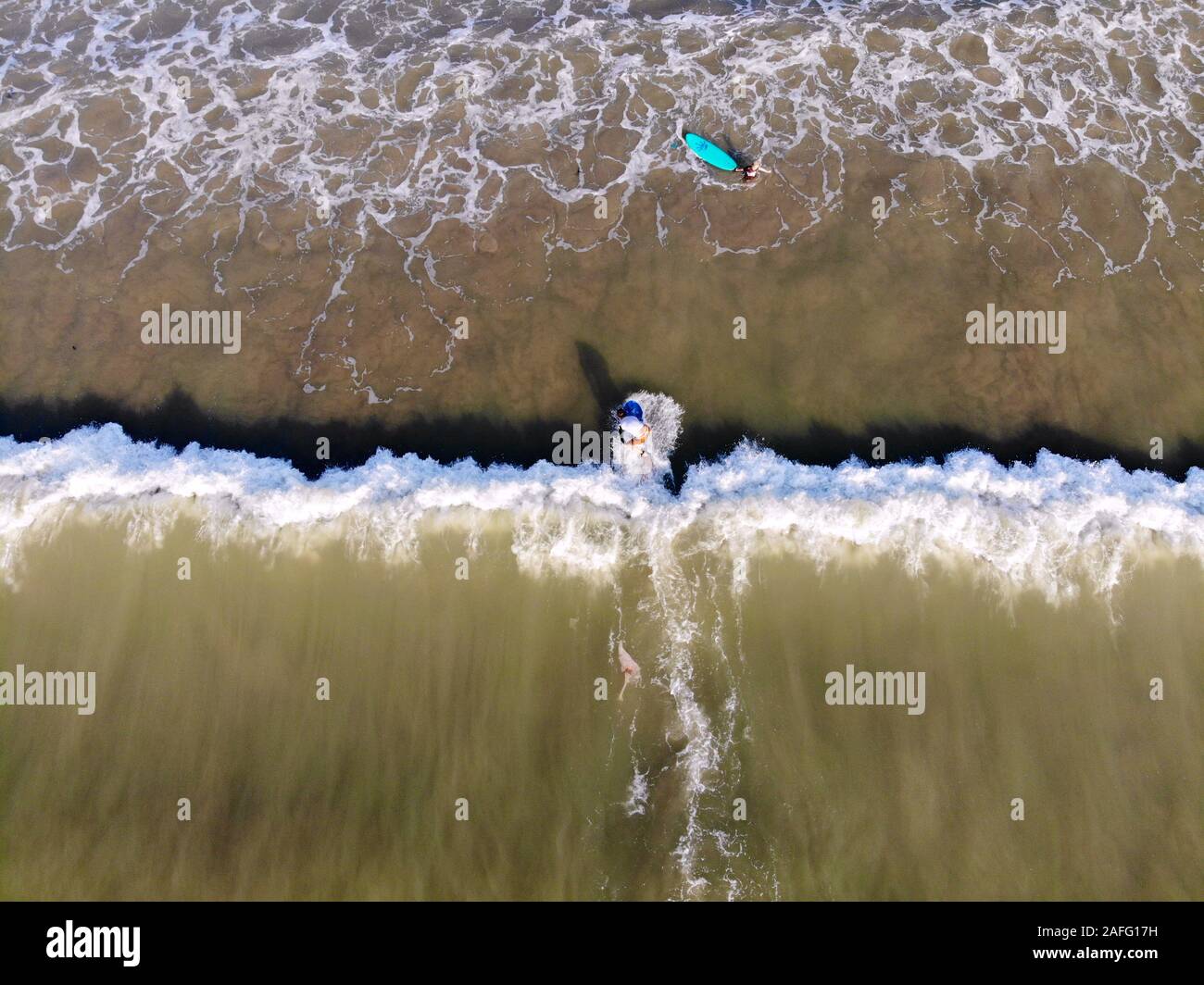 Vista aérea de surfistas esperando las olas en el agua marrón oscuro, en Bali, Indonesia. surfista sobre las olas, los surfistas en su junta esperando las olas Foto de stock