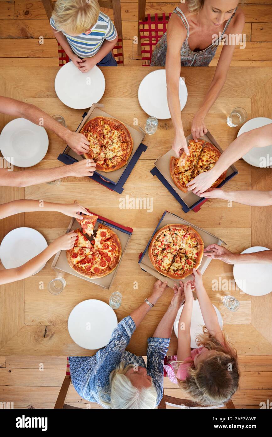 Vista aérea de generación múltiple Familia sentada en torno a una mesa de comer pizza juntos Foto de stock