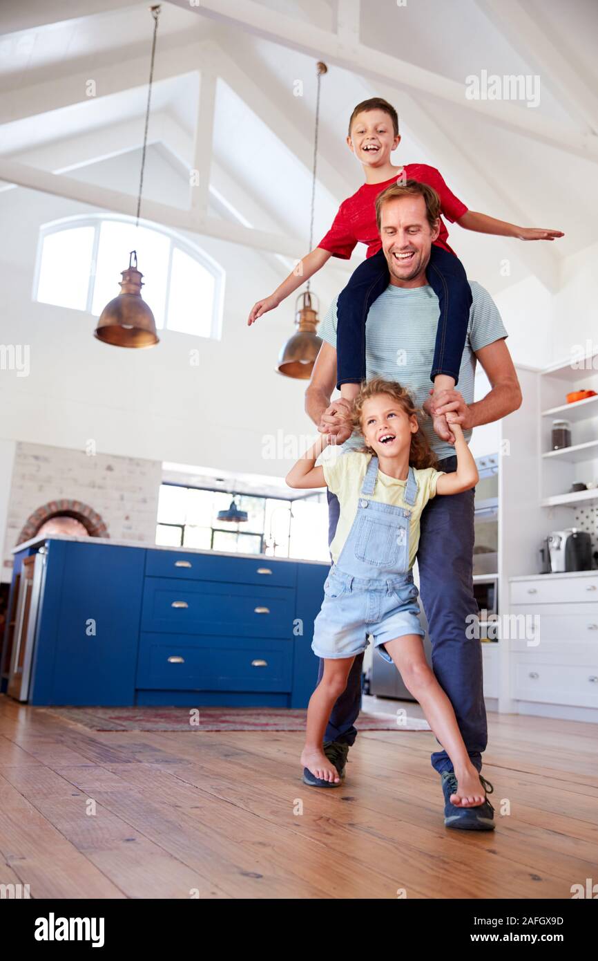 Hija de padres caminando sobre el juego de pies con el hijo en los hombros en casa Foto de stock