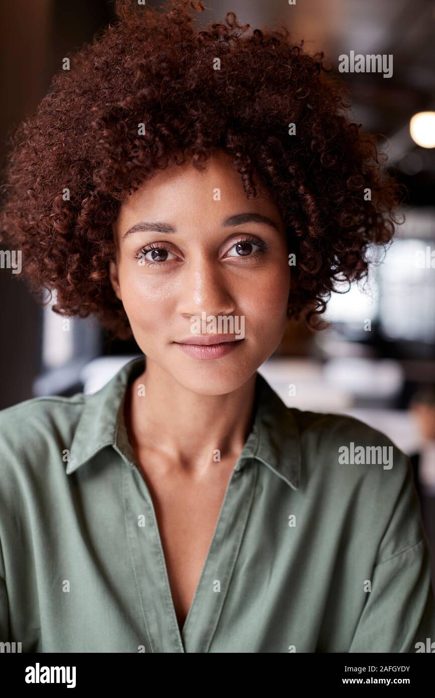 Close Up retrato de mujer negra milenario creativos en una oficina sonriendo ligeramente a cámara Foto de stock