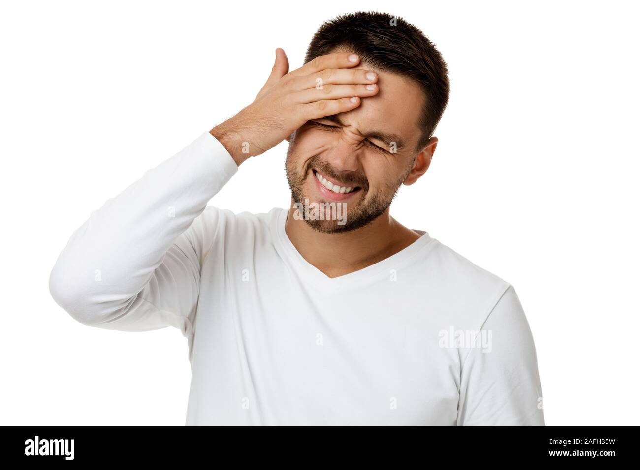 Malestar hombre barbado en casual camiseta blanca mantiene la mano sobre la cabeza aislado sobre fondo blanco. El hombre lamenta sobre algo Foto de stock