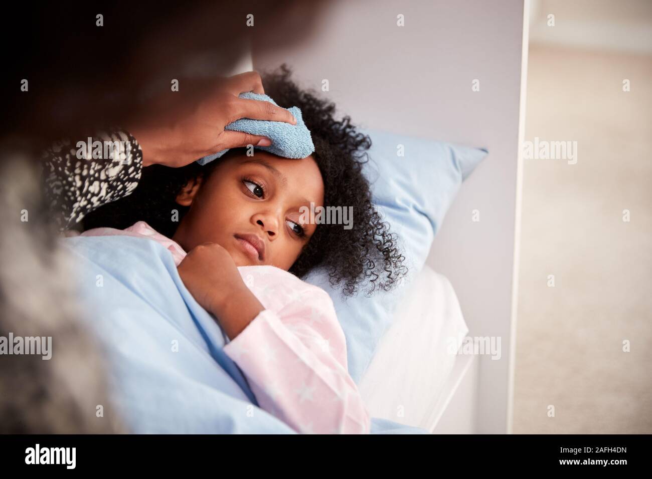 Madre que cuida a su hija enfermo enfermo en cama con la temperatura. Foto de stock