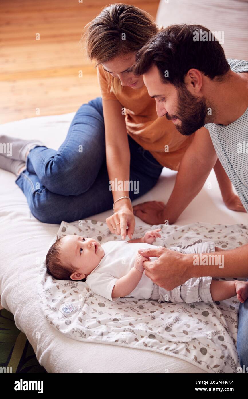 Padres amorosos con bebé recién nacido acostado en la cama, en su casa en Loft Foto de stock