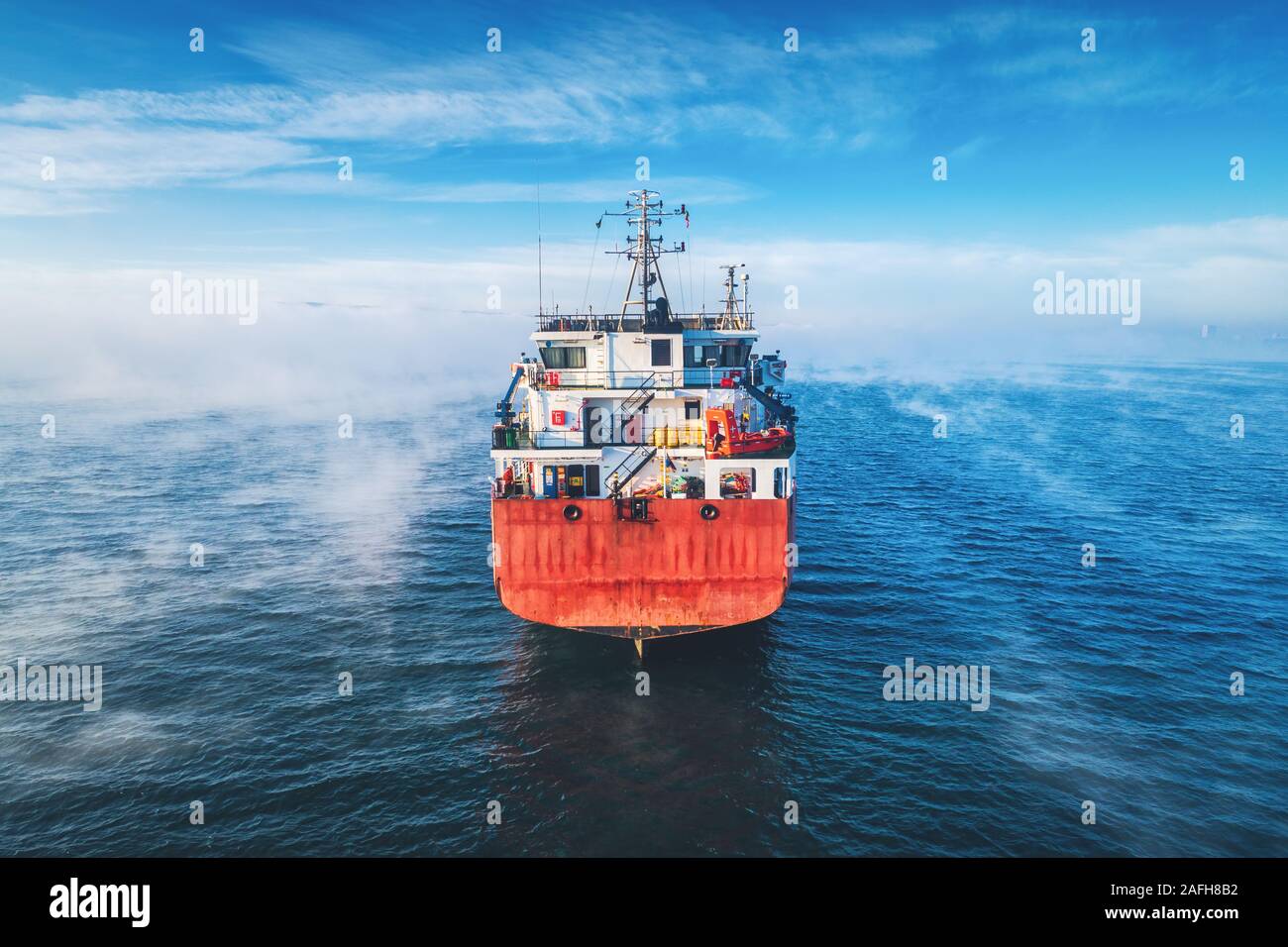 Vista aérea de la carga de un buque portacontenedores velas en mar de niebla barco grúa, trabajando para la entrega de contenedores de entrega. Foto de stock