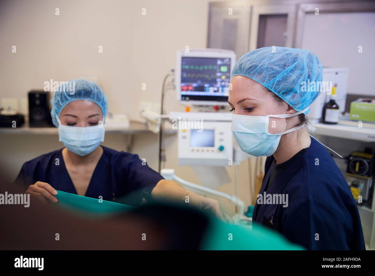 El equipo quirúrgico de mujeres trabajando sobre el paciente en el quirófano del hospital Foto de stock