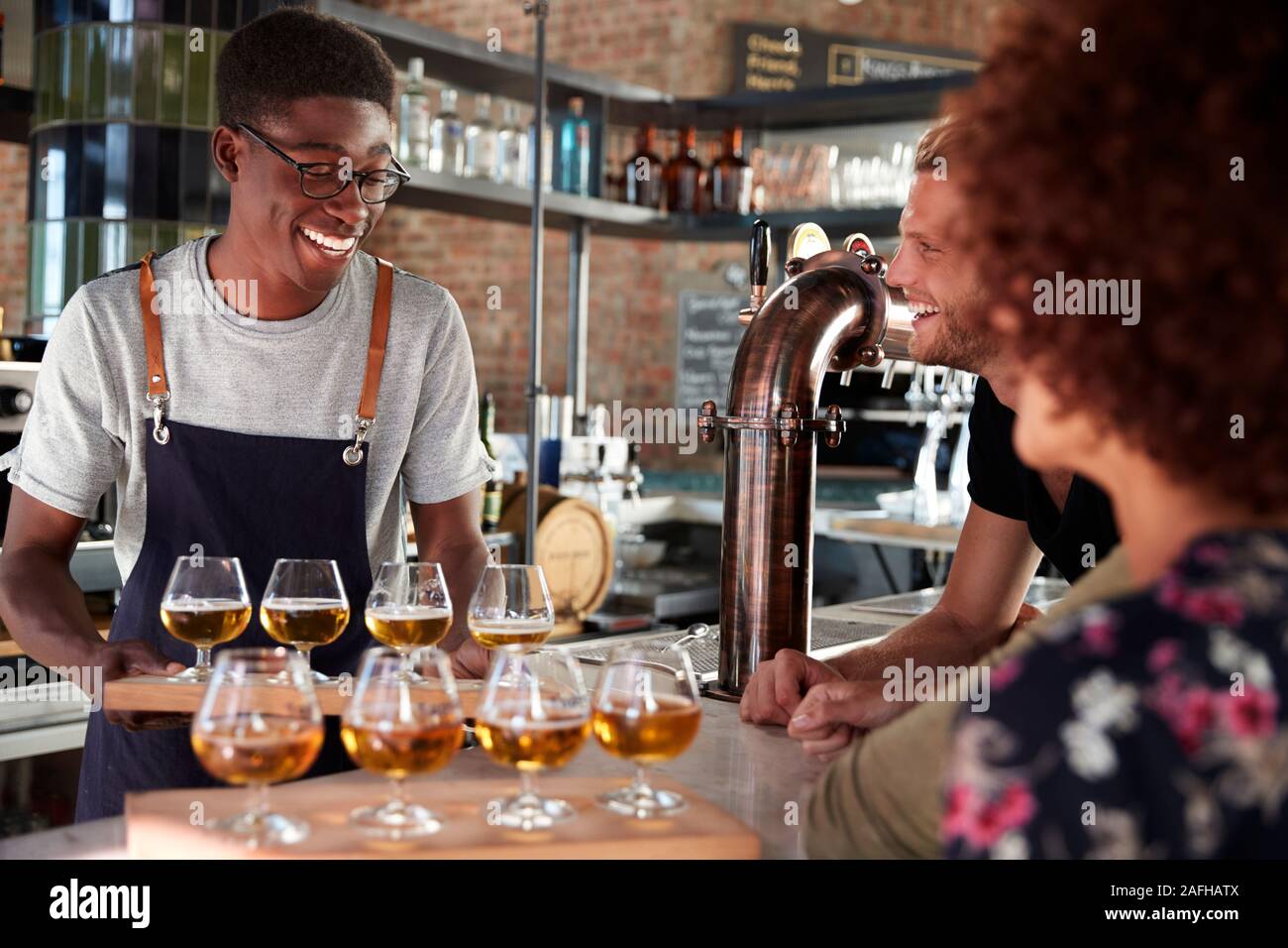 Camarero sirviendo a un grupo de Amigos de la cata de cerveza en el bar Foto de stock