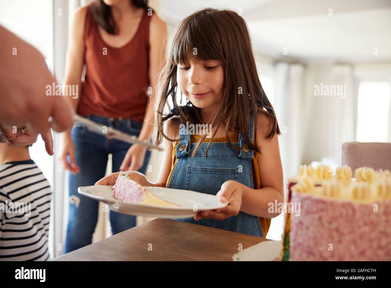 Niña de seis años que se sirvió pastel de cumpleaños durante una celebración familiar, cerrar Foto de stock