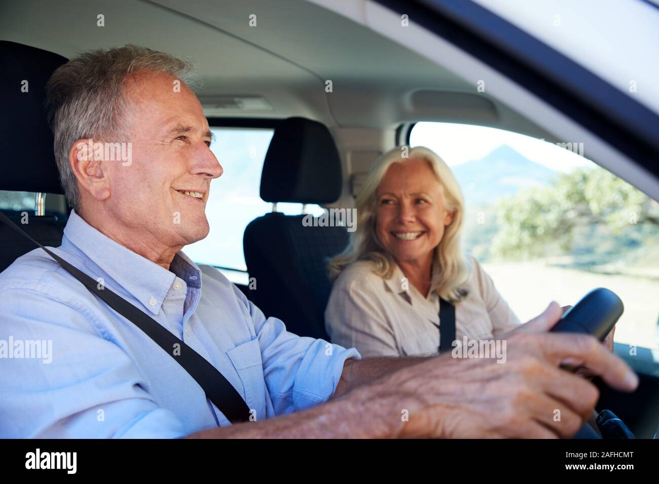 Hombre blanco senior en coche, su esposa junto a él en el asiento del pasajero delantero, cerrar, vista lateral Foto de stock