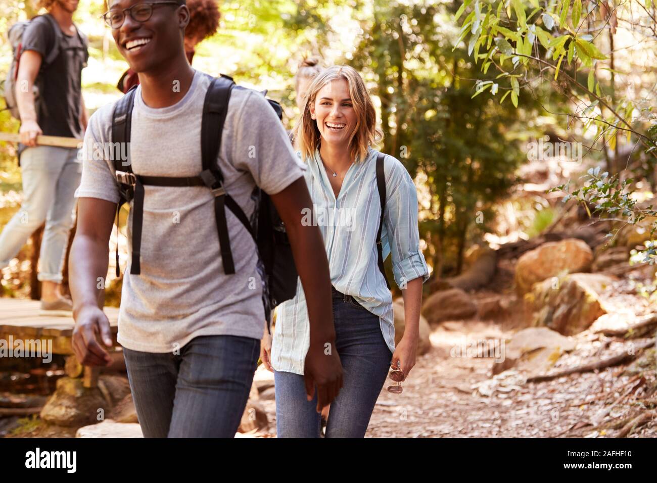 Grupo milenario de feliz amigos caminando juntos durante una caminata en el bosque, cerrar Foto de stock