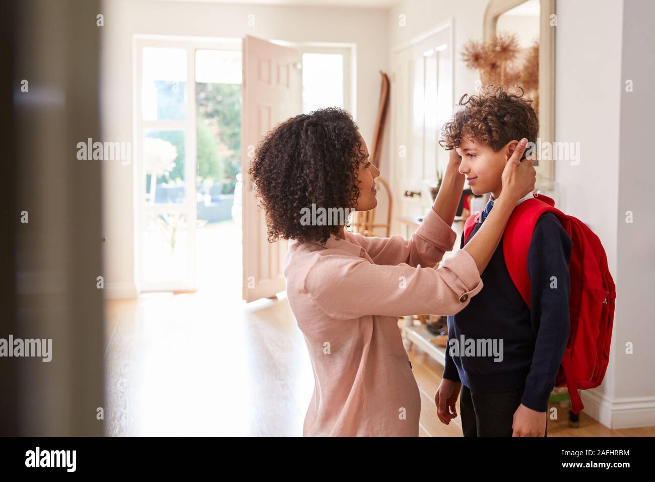 Madre soltera en casa recibiendo hijo Uniforme listo para su primer día de escuela Foto de stock