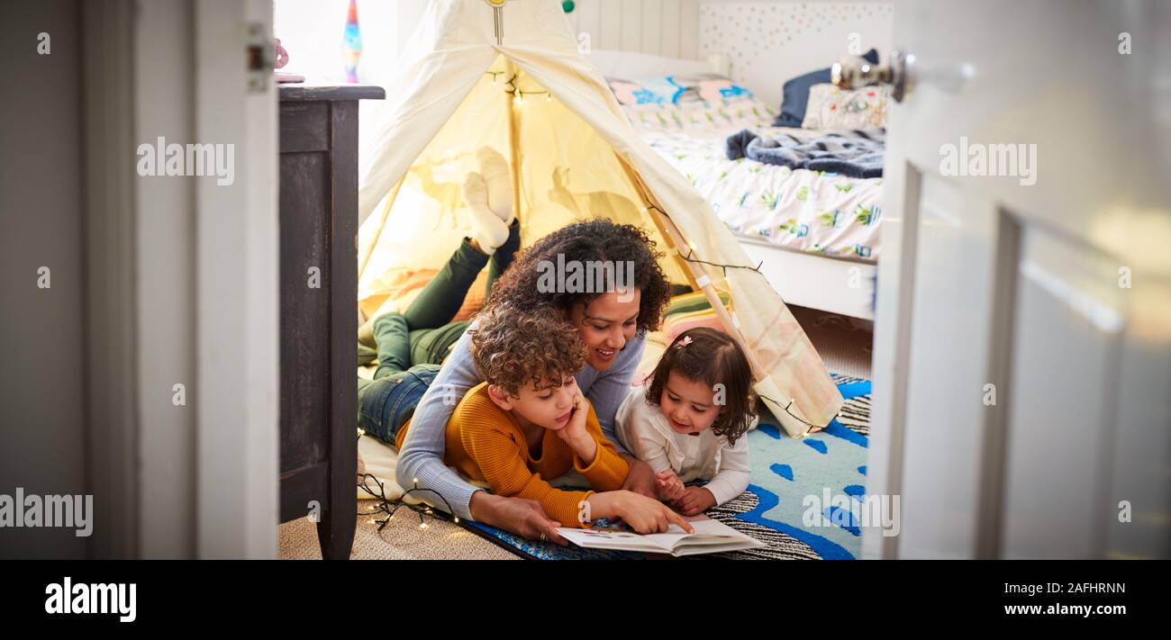 Lectura de madre soltera con hijo e hija en Den en dormitorio en casa Foto de stock