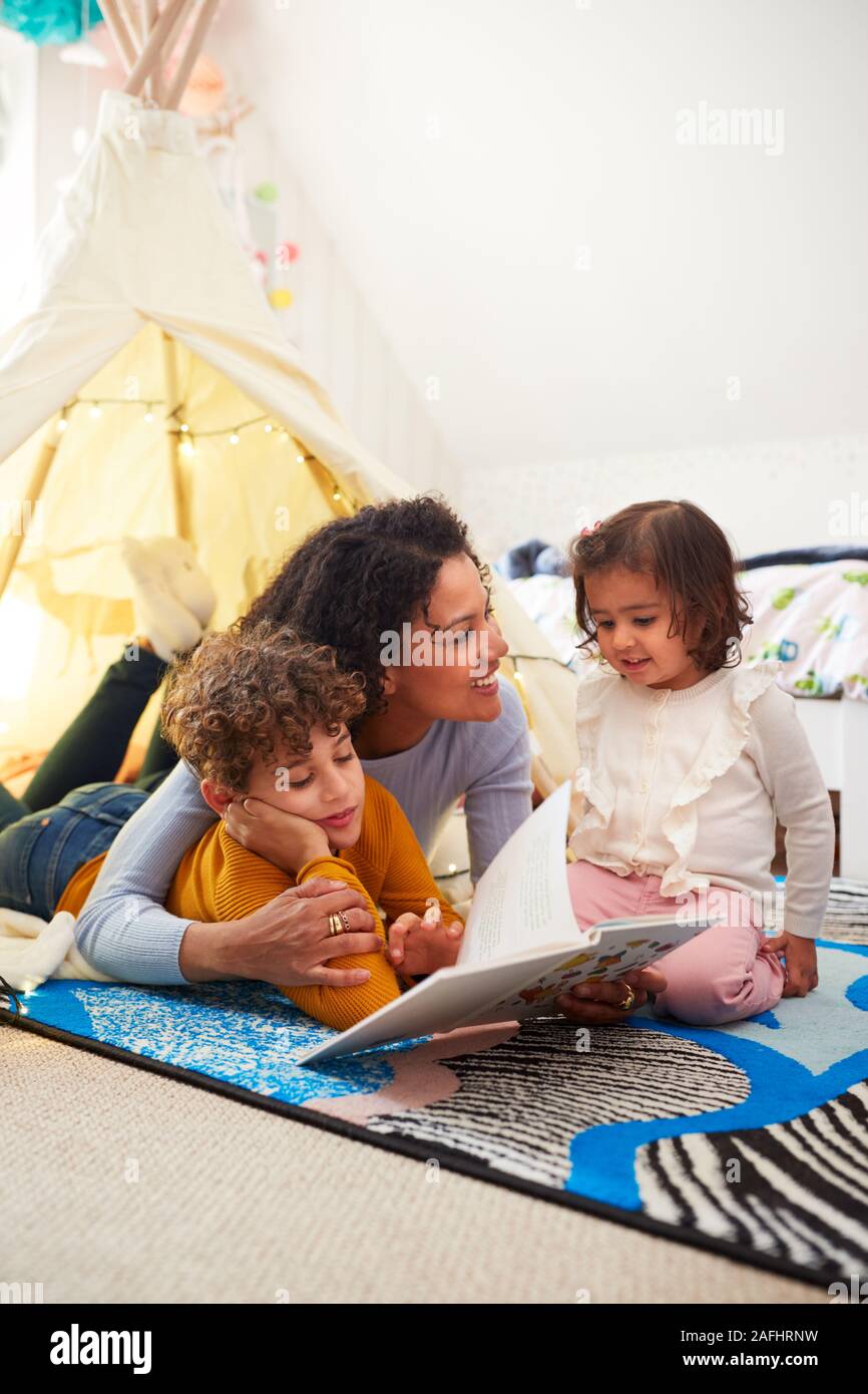 Lectura de madre soltera con hijo e hija en Den en dormitorio en casa Foto de stock