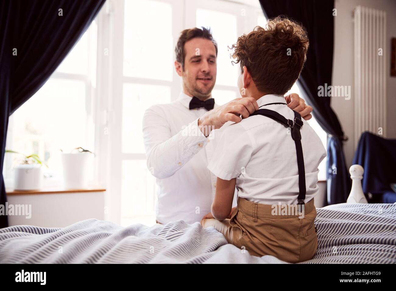 Padre e Hijo vistiendo trajes coincidentes preparándose para la boda en casa Foto de stock
