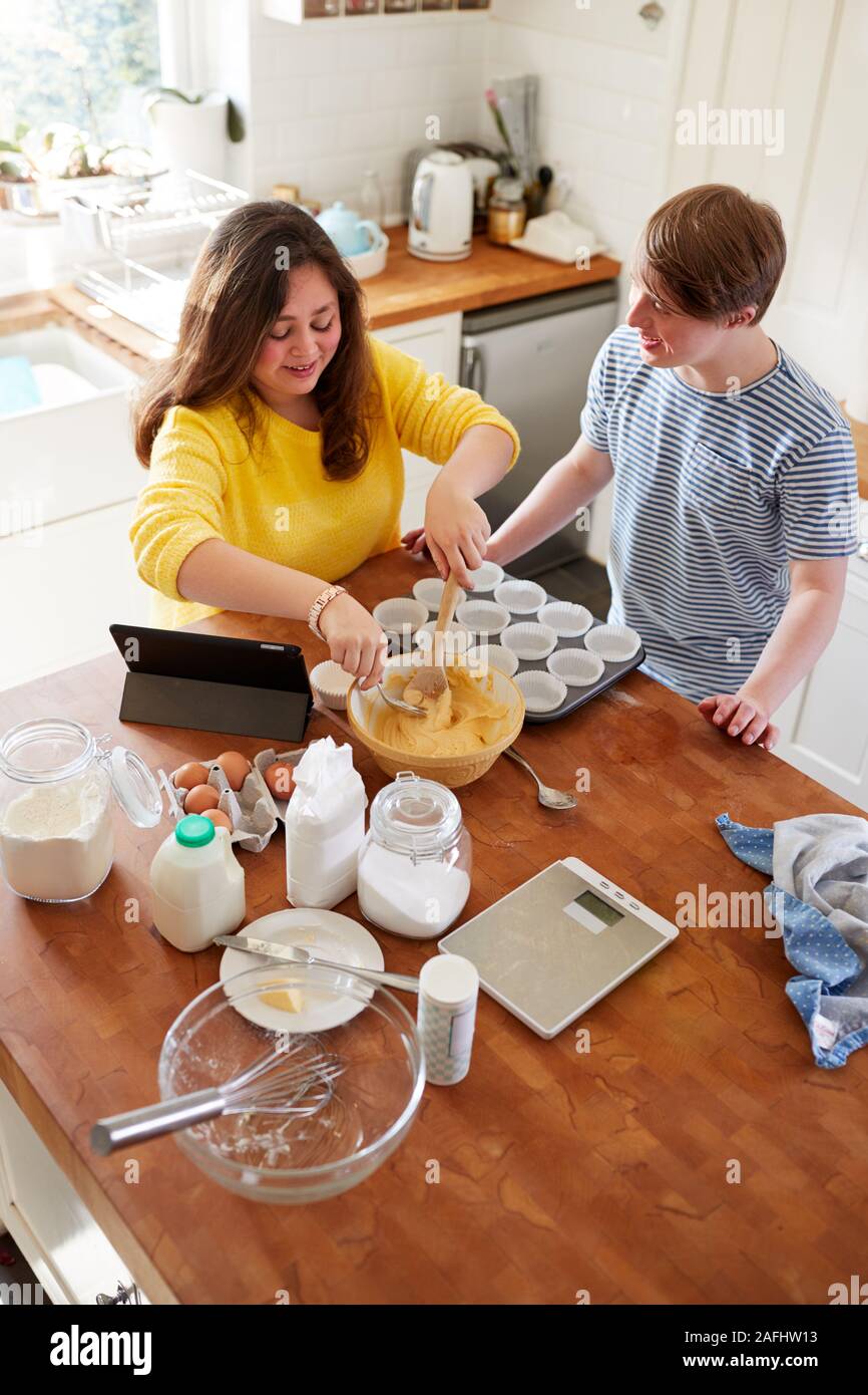 El síndrome de Downs joven pareja hornear las magdalenas en la cocina de casa Foto de stock