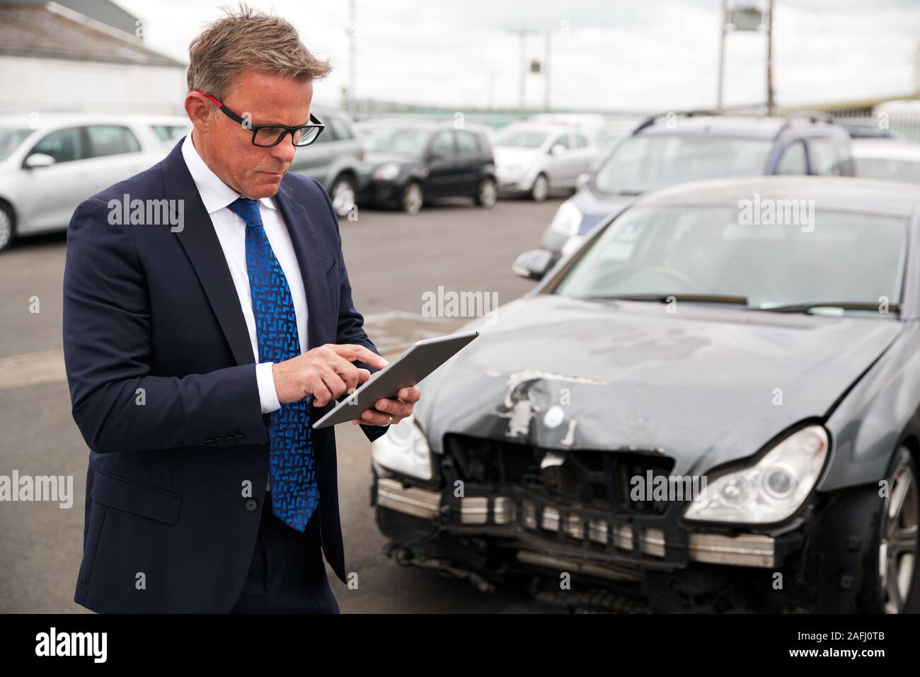 Ajustador de seguro pérdida masculina con tableta digital Inspeccionando daños al coche de accidente de automóvil Foto de stock