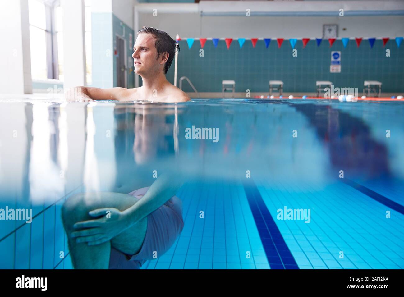 Parte vista submarina de nadador masculino calentando en Piscina Foto de stock