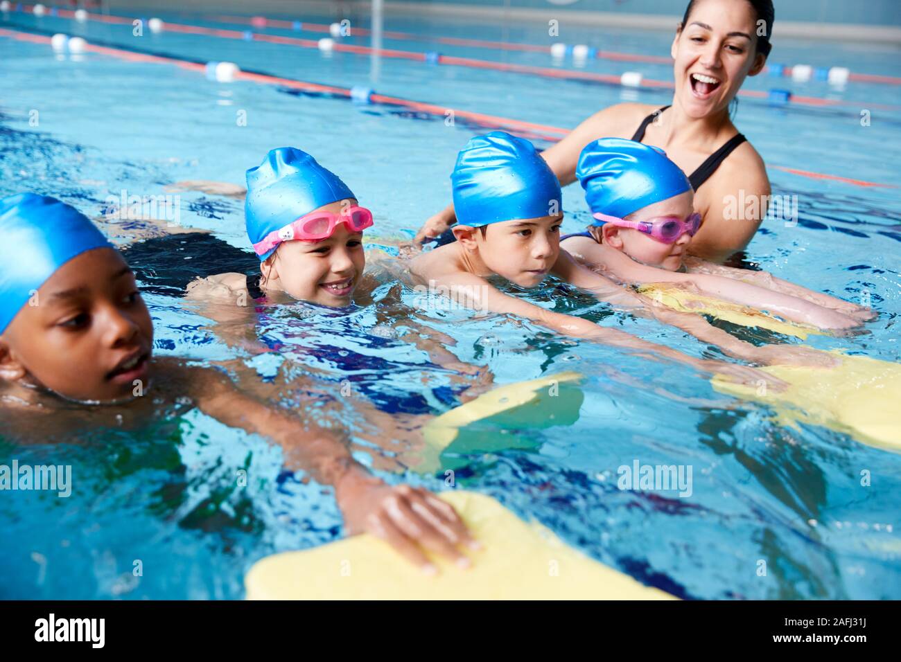 Entrenador femenino en agua, dando grupo de niños Lección de Natación en Piscina cubierta Foto de stock