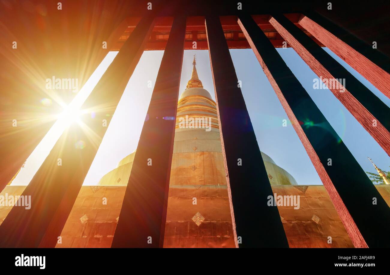 Pagoda dorada vista desde la ventana vintage en Wat Phra Singh en Chiang Mai, Tailandia, con destellos de luz por la mañana. Destino turístico landmark Foto de stock
