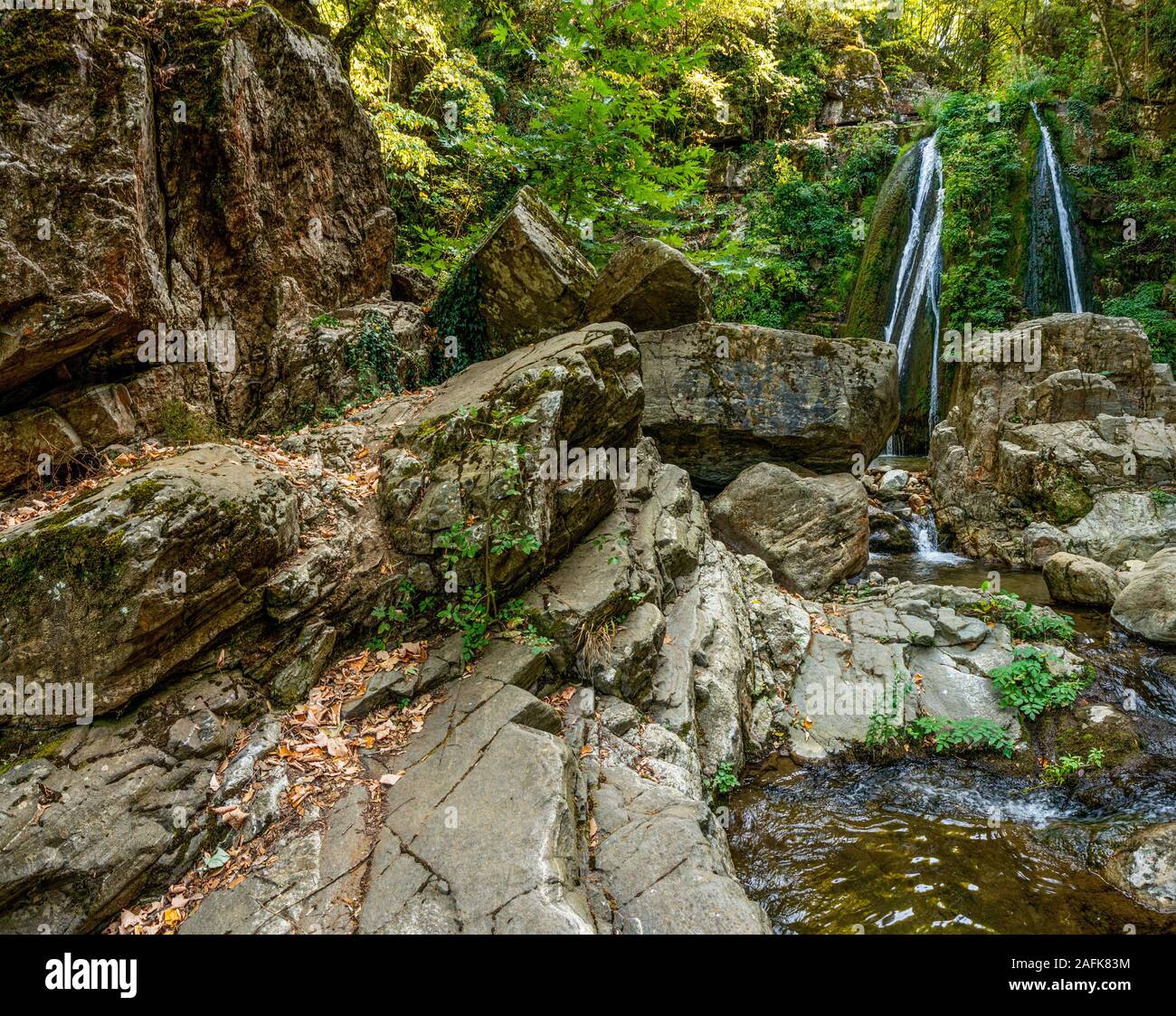 Cascada de agua y rocas en el fondo de árboles en Grecia horizontal Foto de stock