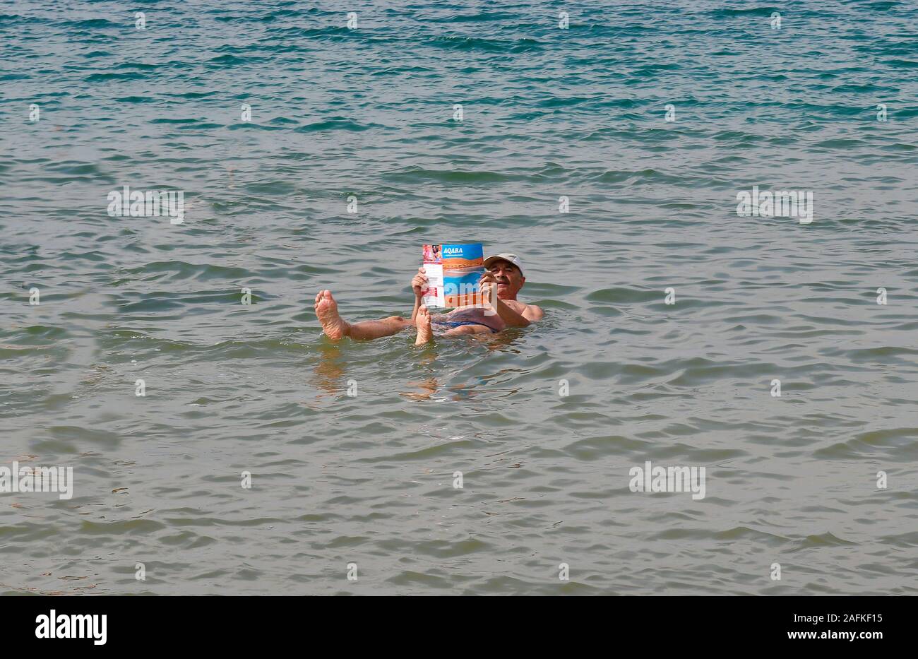 Jordania, el hombre lea el folleto en el Mar Muerto un Salt Lake 400m bajo el nivel del mar, la gente se hundirá debido al alto grado de salinidad Foto de stock