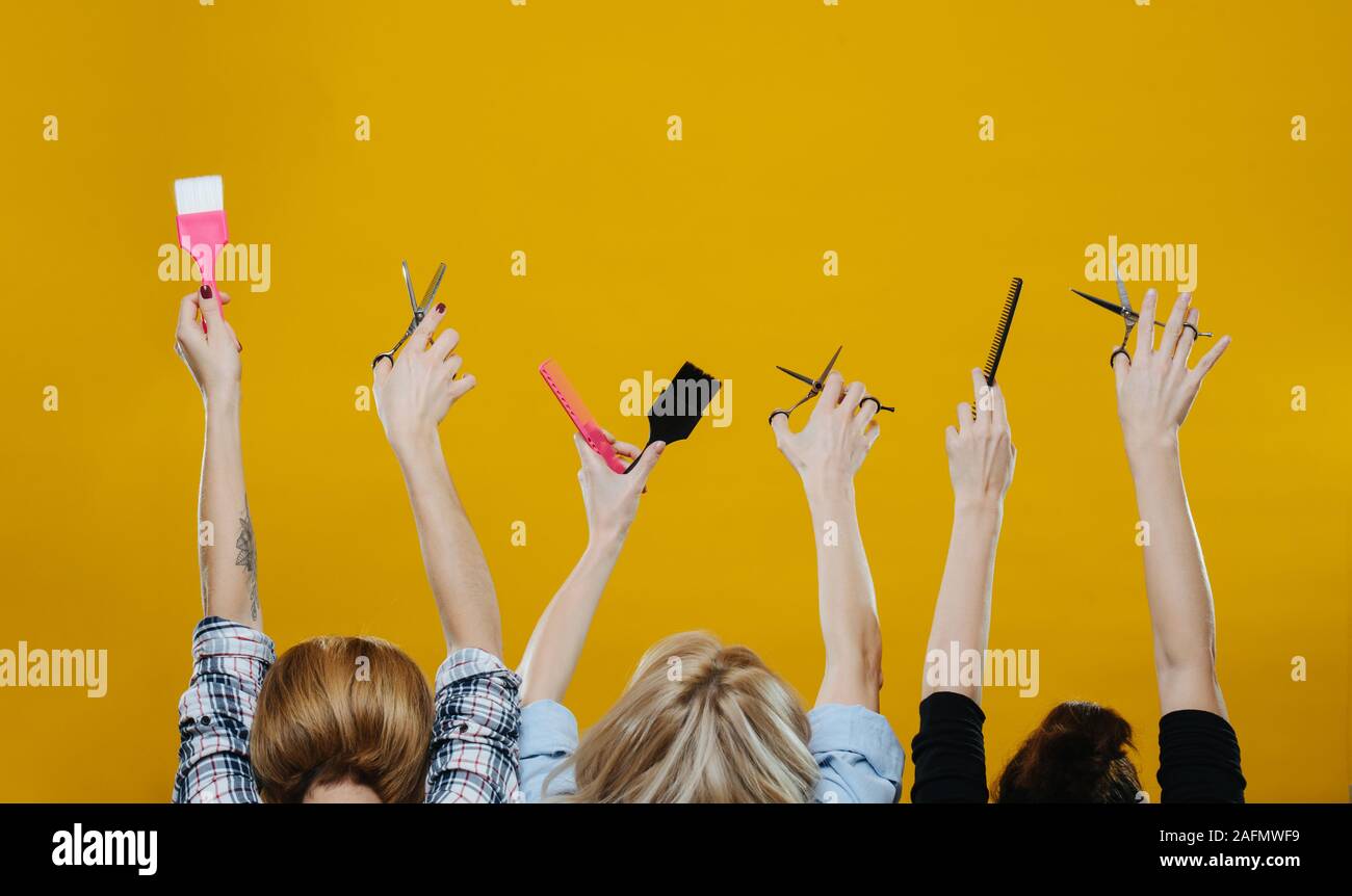 Las mujeres con sus manos en el aire la celebración de peluquería  herramientas sobre amarillo Fotografía de stock - Alamy