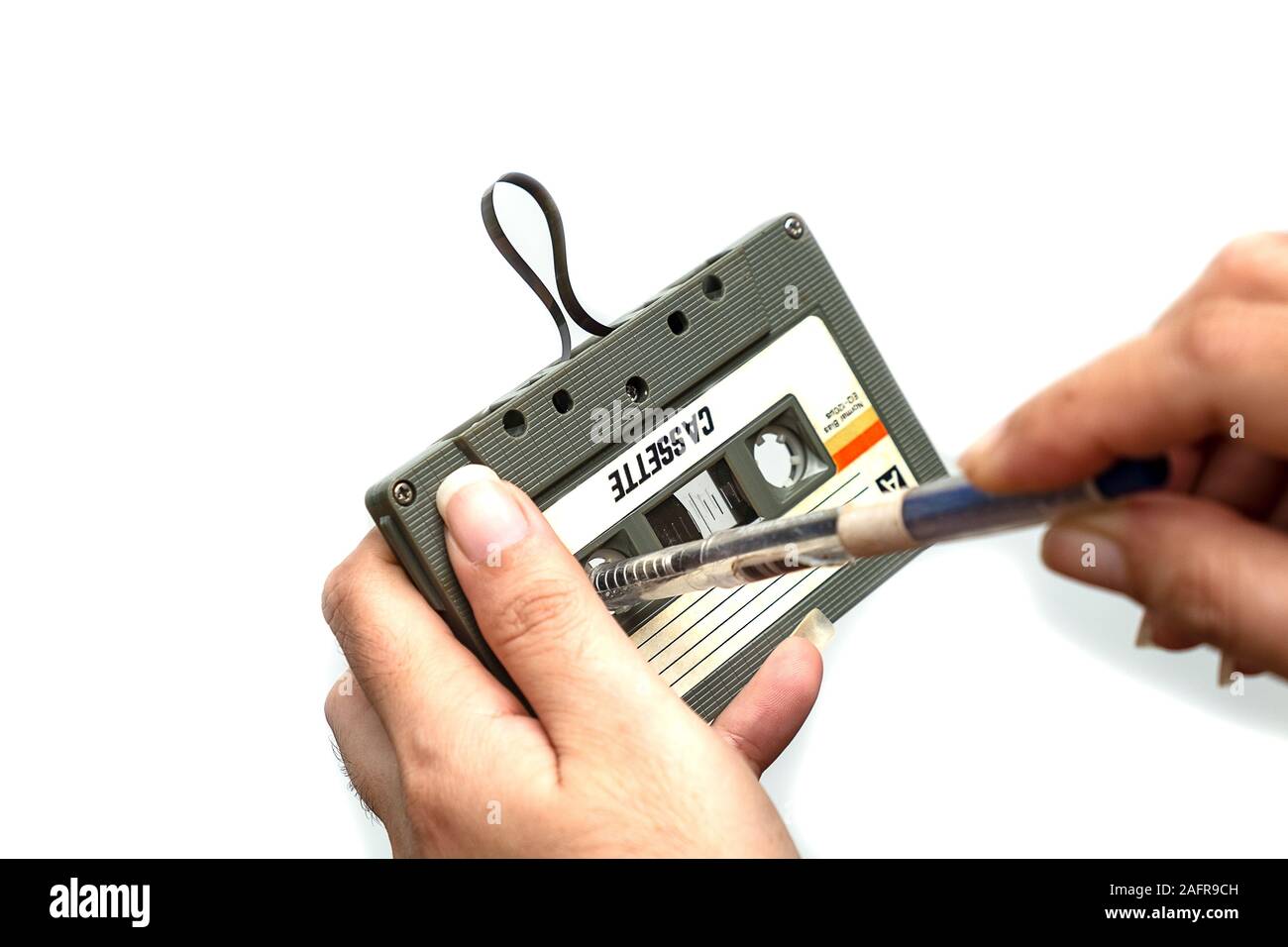 Las mujeres rebobinar una cinta casete compacto Vintage sobre fondo blanco, cerca de conjunto de antiguas cintas de audio, Retro Foto de stock