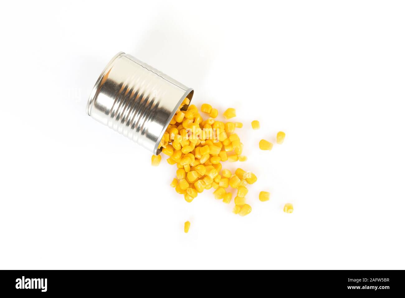 Una lata de maíz derramado sobre una superficie blanca Foto de stock