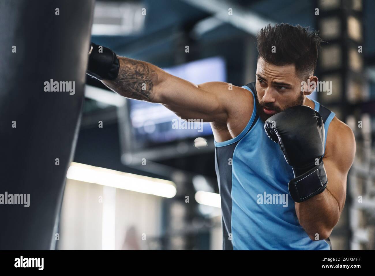 Chico deportivo punzonado saco de boxeo en el gimnasio Fotograf a