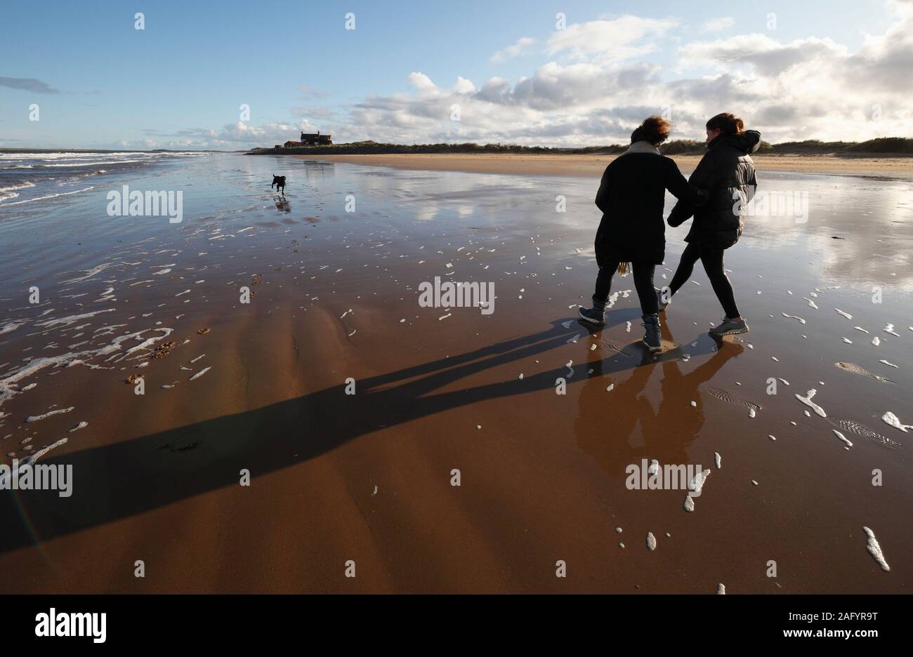 Madre e hija y Labrador negro en la playa de Brancaster en la costa de North Norfolk. Foto de stock