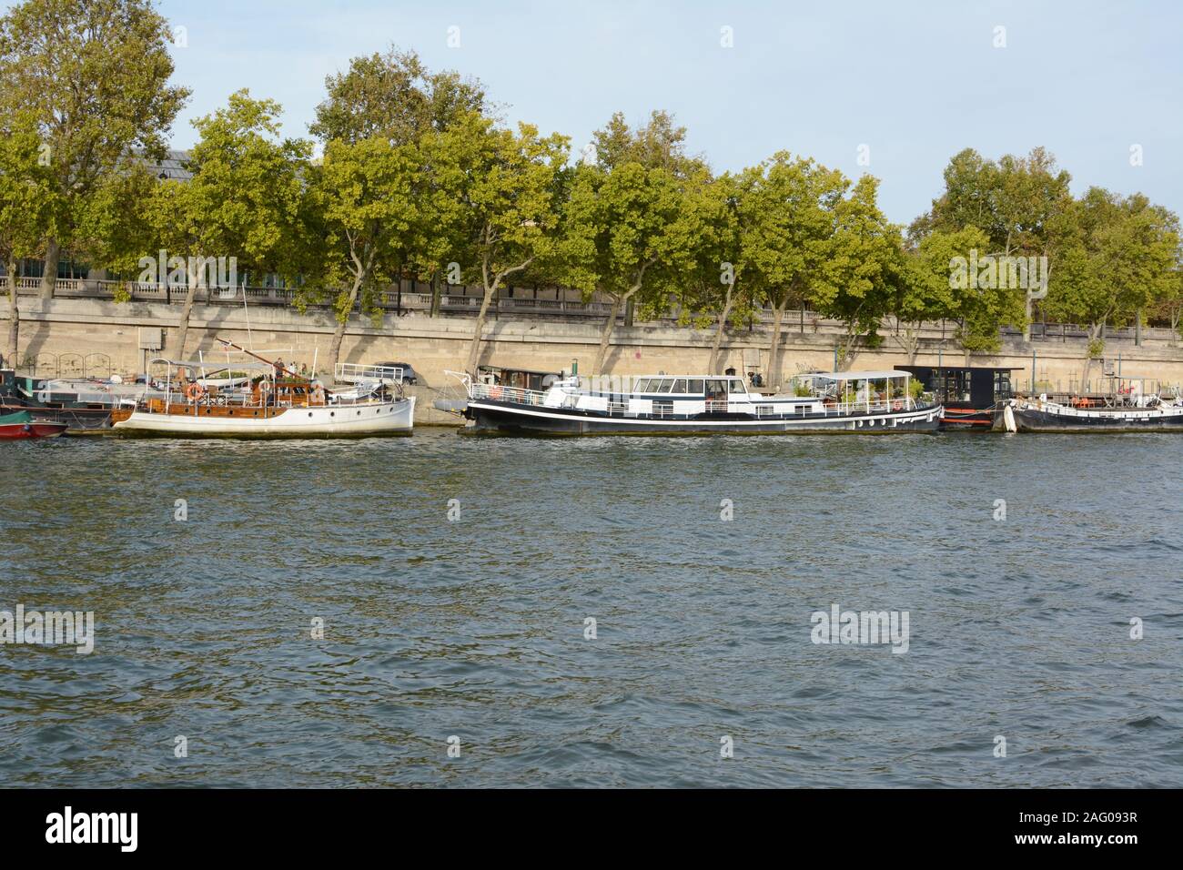 París, Francia - 16 de septiembre de 2019: pequeñas barcas amarrados en el Sena en París el 16 de septiembre de 2019. Contenedor de plantas y muebles de patio en la b Foto de stock