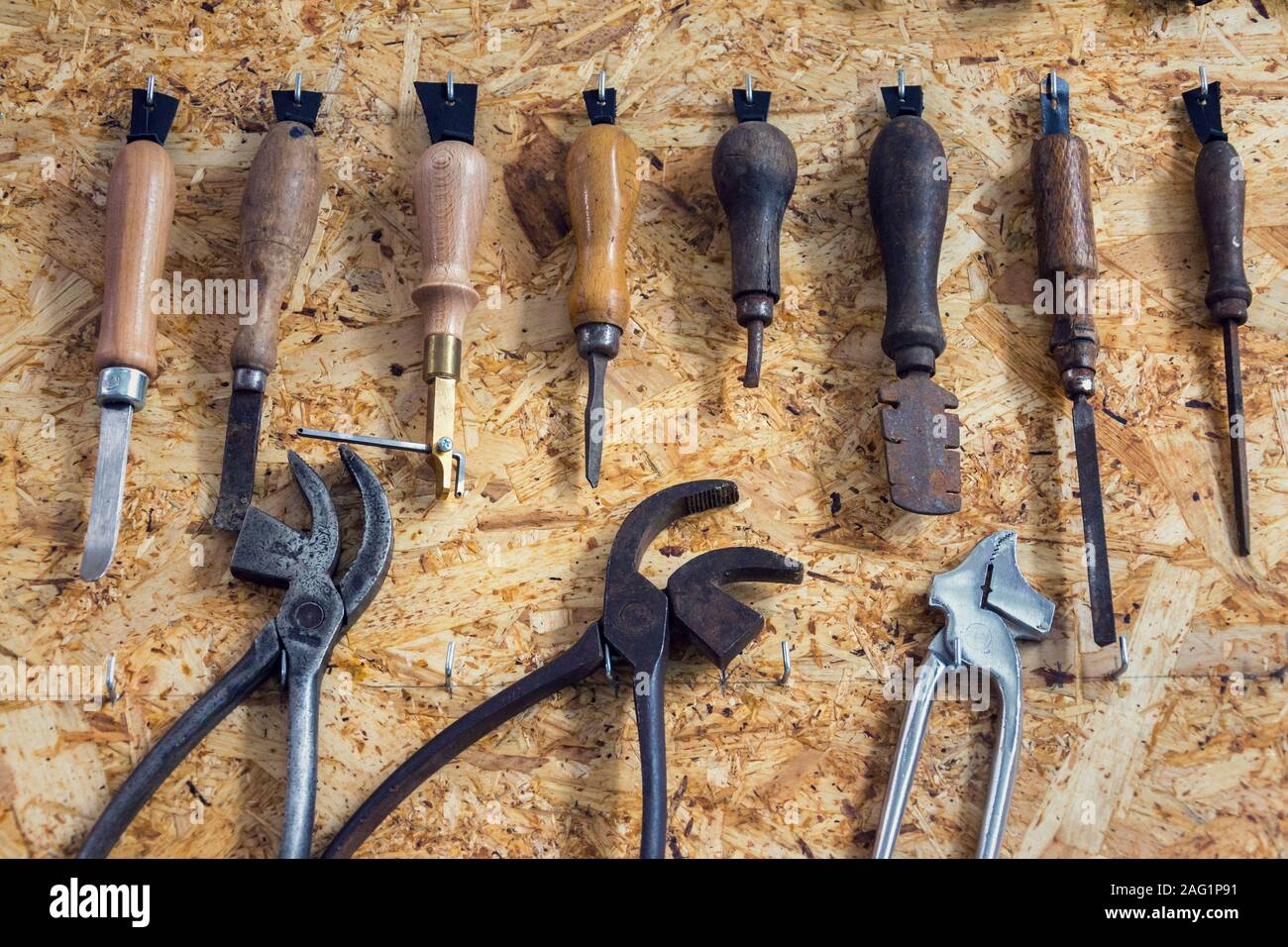 Grupo de viejos zapateros herramientas para la producción de calzado  artesanal, punzones y pinzas para el cuero en aglomerado de madera, de  fondo plano vista laicos Fotografía de stock - Alamy