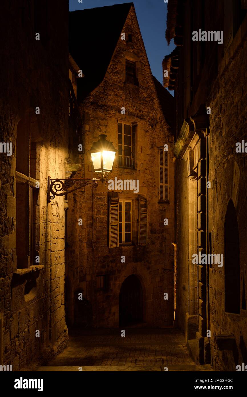 Licencia e impresiones en MaximImages.com - dramático paisaje crepúsculo de una antigua calle histórica con casas de piedra iluminadas por una lámpara de la calle en un medieval Foto de stock