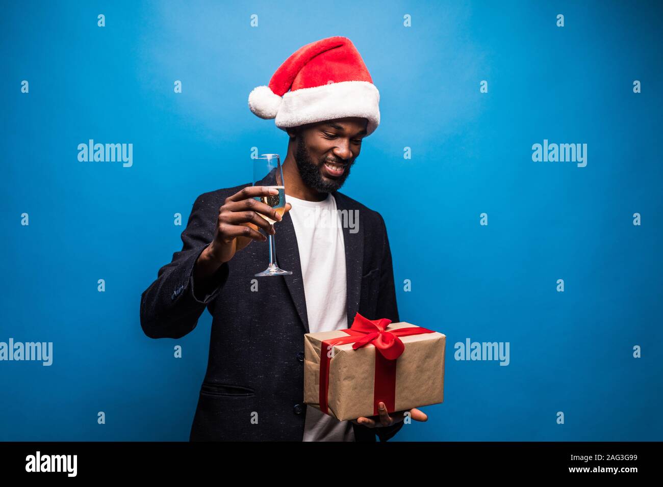 Hombre africano llevar gorro de Papá Noel con champán y caja de regalo  contra el fondo azul. Feliz joven chico negro disfrutando de la víspera de  Navidad Fotografía de stock - Alamy