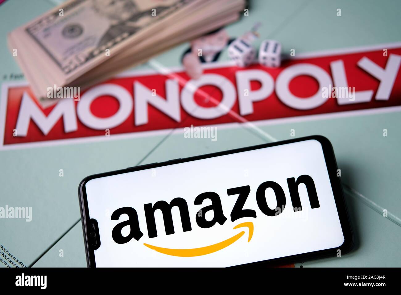 Logotipo de Amazon en smartphone colocado junto al monopolio juego con dinero real. Fotografía conceptual. Foto de stock