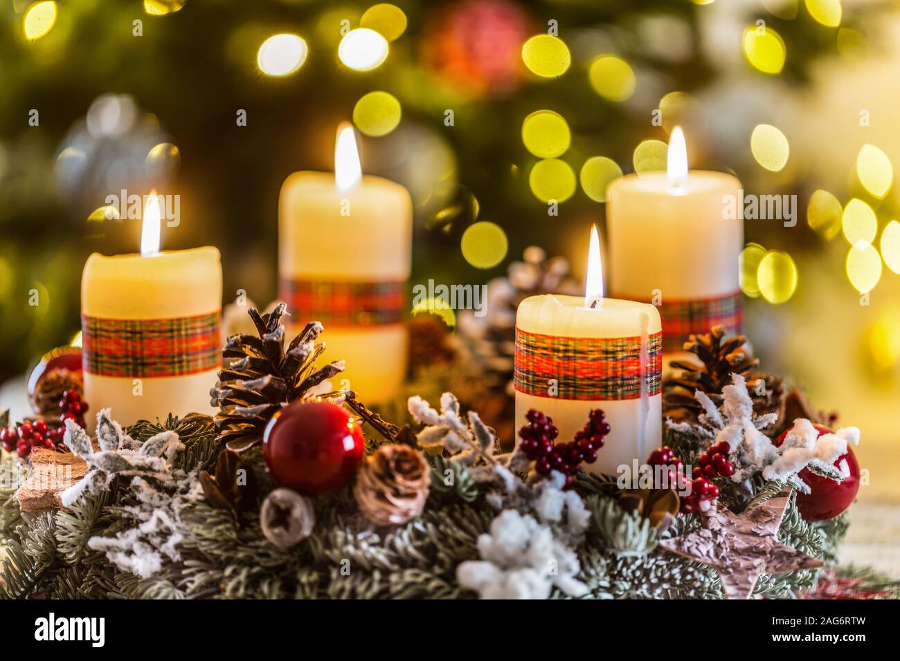 Corona de Adviento con cuatro velas encendidas blanco bolas de Navidad y adornos en un fondo de madera con ambiente festivo Foto de stock