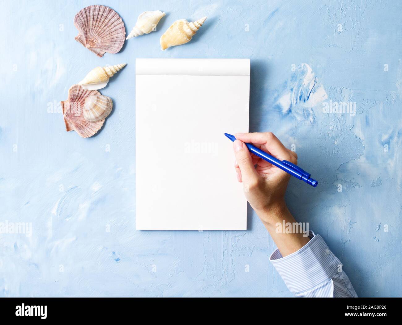 Mujer escribe en el bloc de notas en un cuadro azul piedra, maquetas con  bastidor de concha, vista superior, la planificación de vacaciones en el  mar Fotografía de stock - Alamy